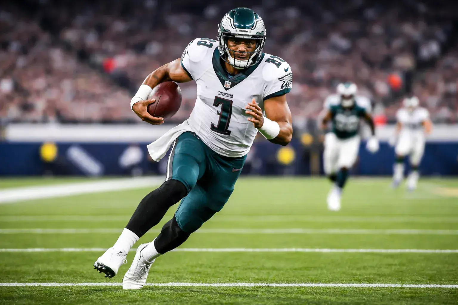 Mobile NFL quarterback running with football toward end zone